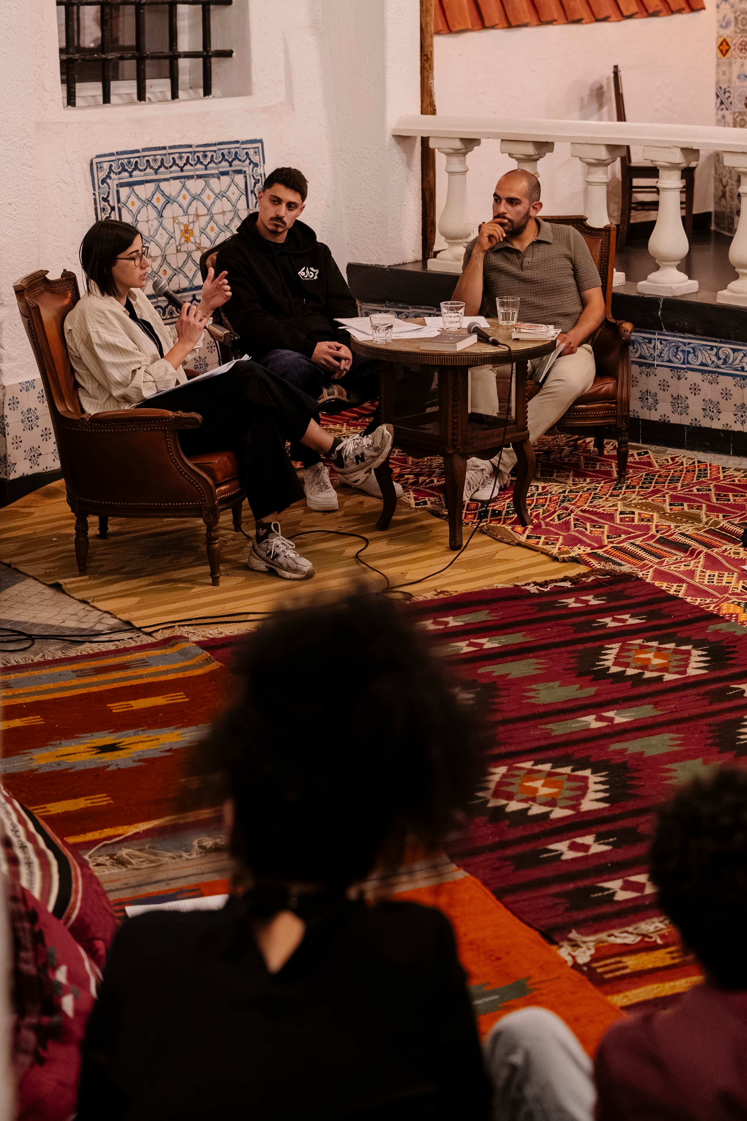 Speakers in conversation over a low table at a House talk.