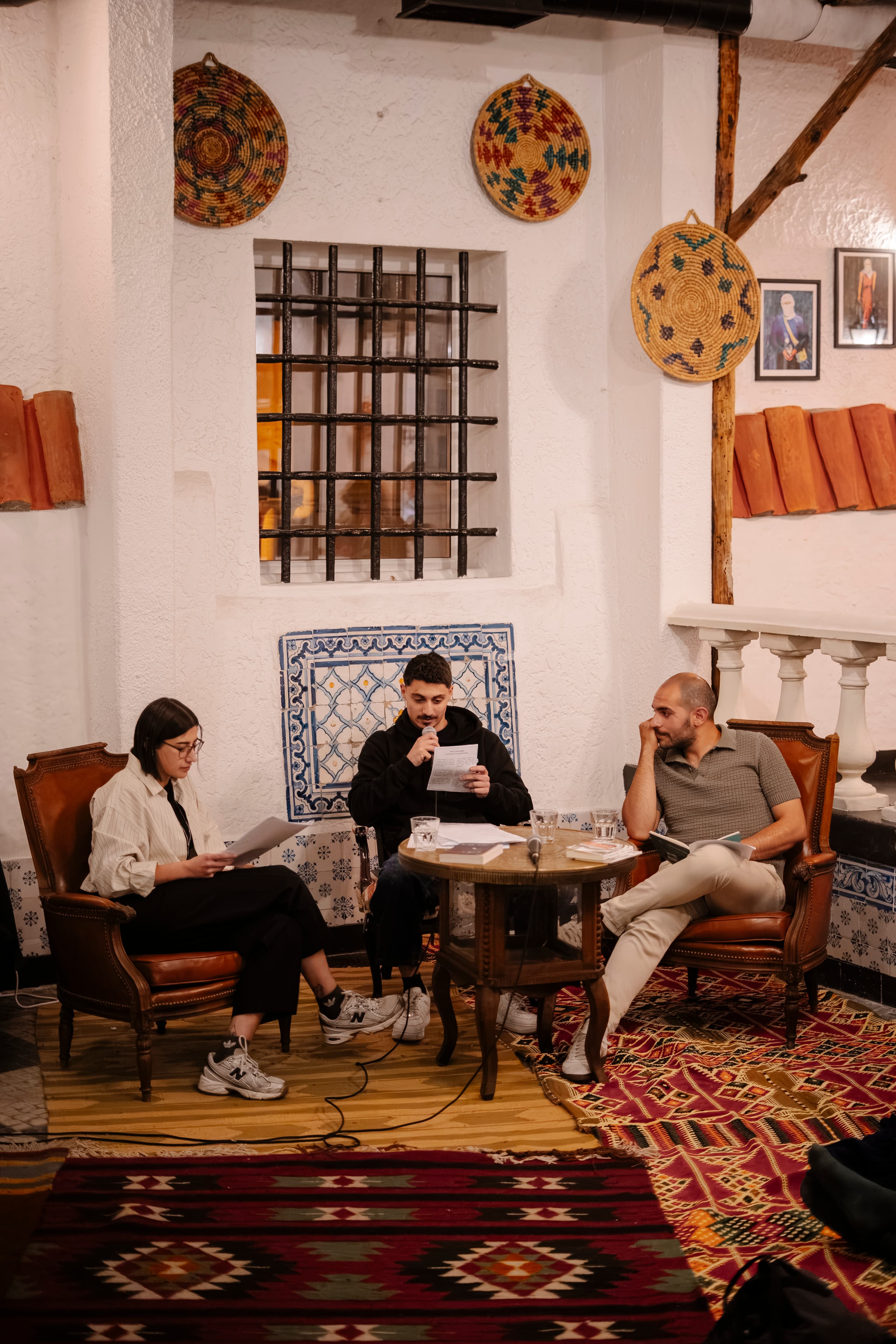 Readers sharing pages aloud in the armchairs of a House gathering.