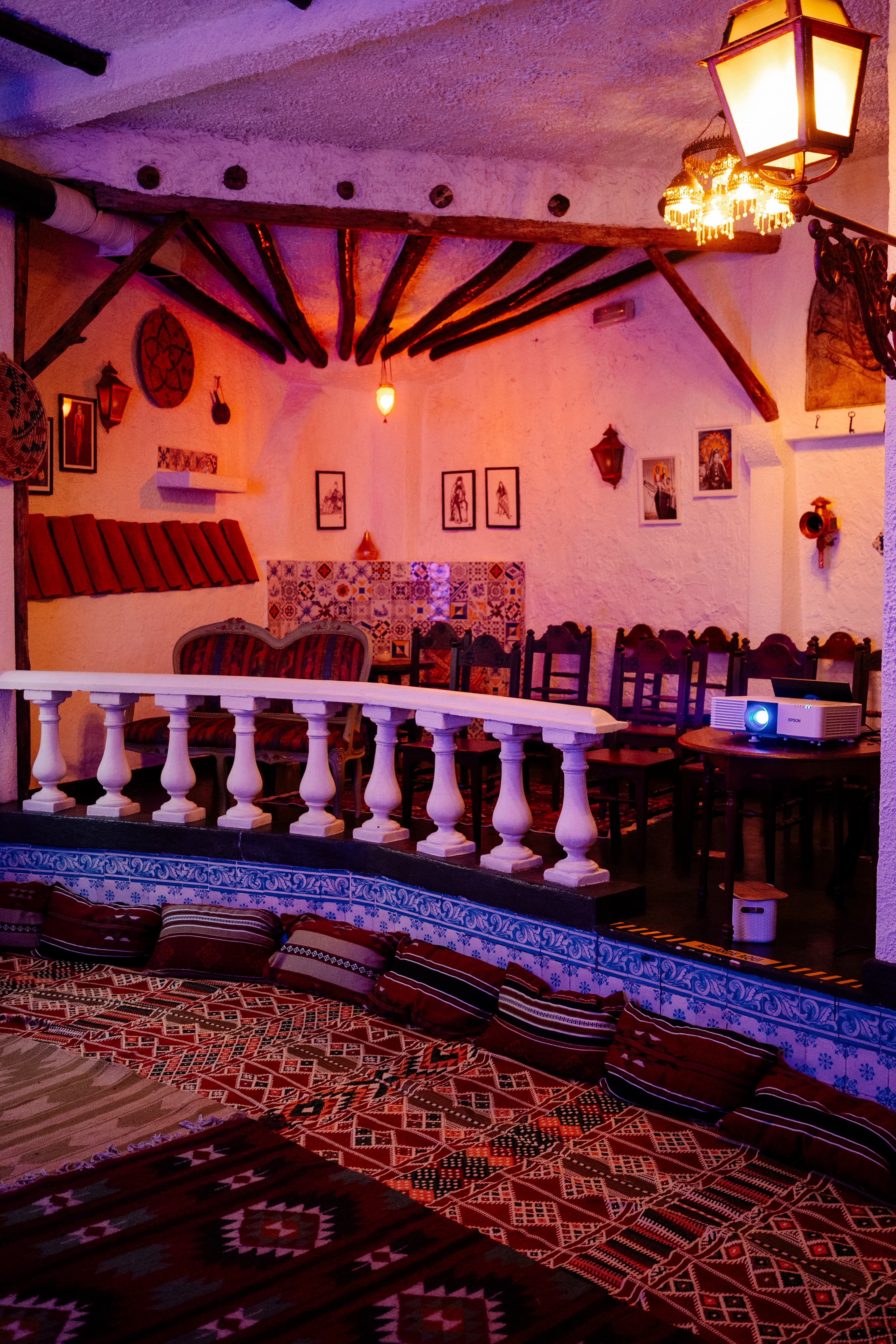The café room set for the evening — cushioned seating, a balustrade, a projector ready.